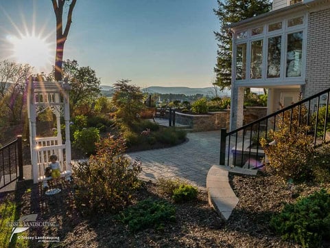 A stone walkway leading to a house with a view of the sun.