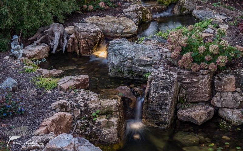 A pond with rocks and a waterfall.