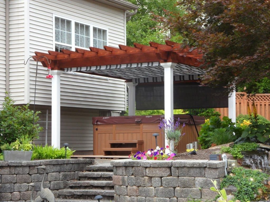A hot tub with a pergola in front of a house.