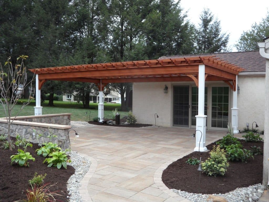 A patio with a pergola and landscaping around it.