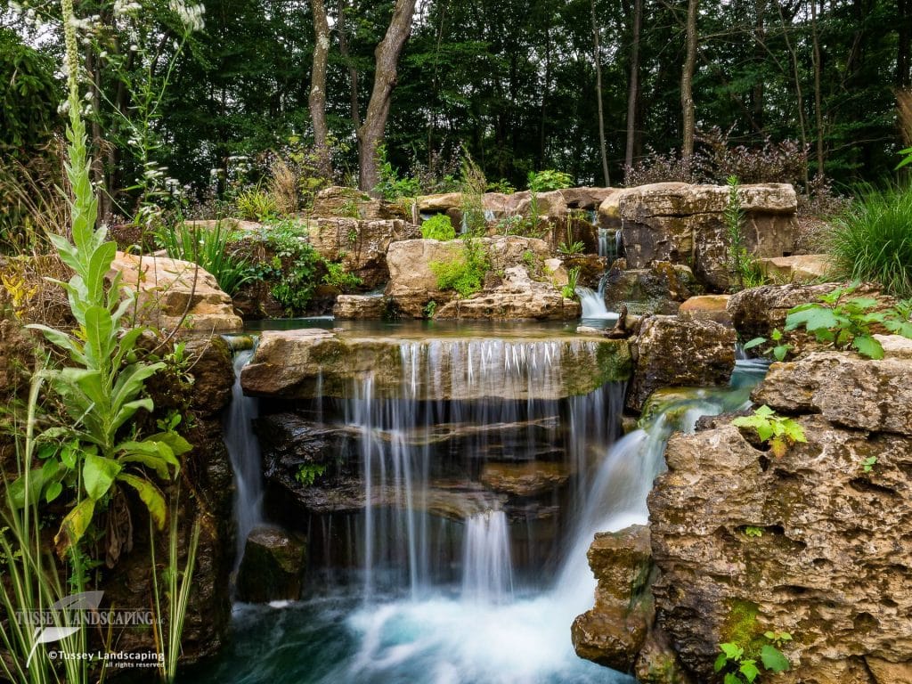 A waterfall in a garden surrounded by rocks.
