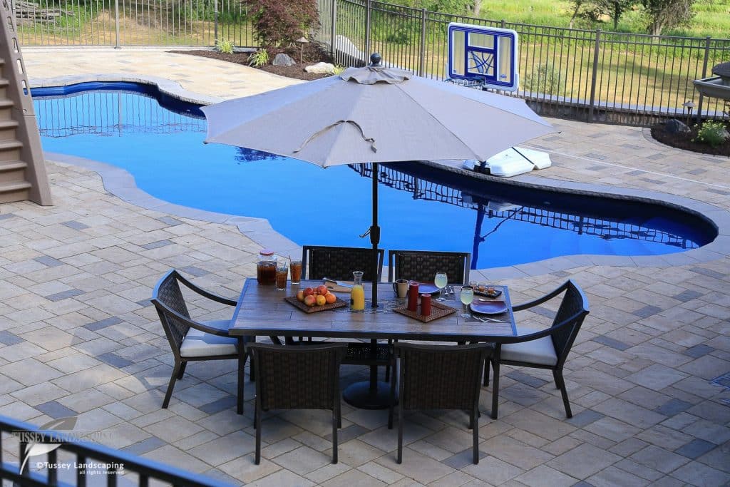 A patio with a table and chairs next to a pool.