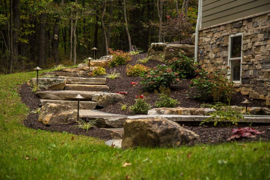 A stone walkway leading to a house in a wooded area.