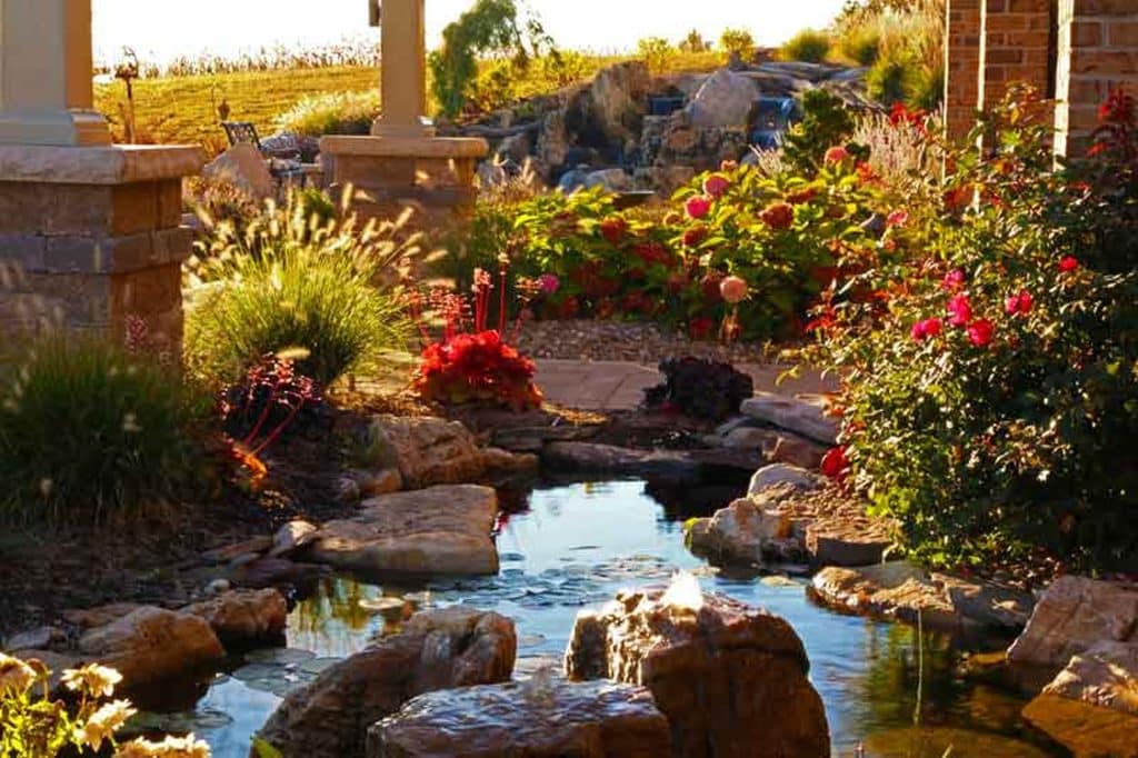 A garden with a pond and rocks in the middle.