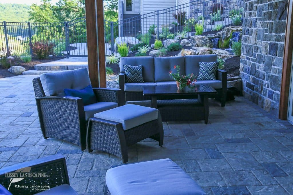 A patio with patio furniture and a stone wall.