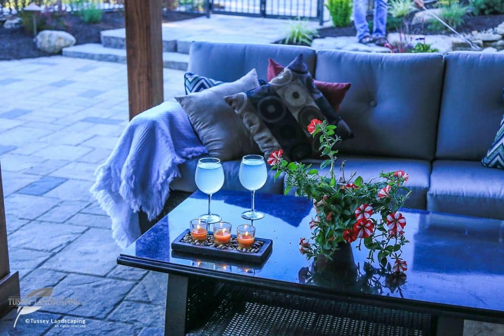 A patio with a couch and two glasses of wine.
