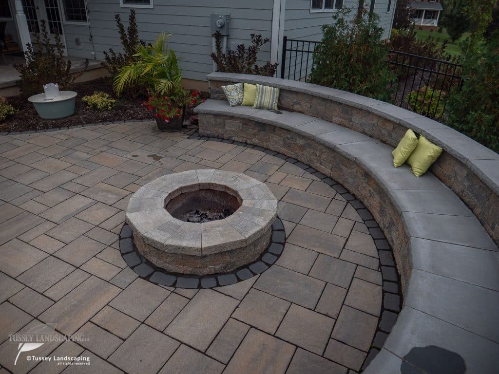 A patio with a fire pit and a bench.