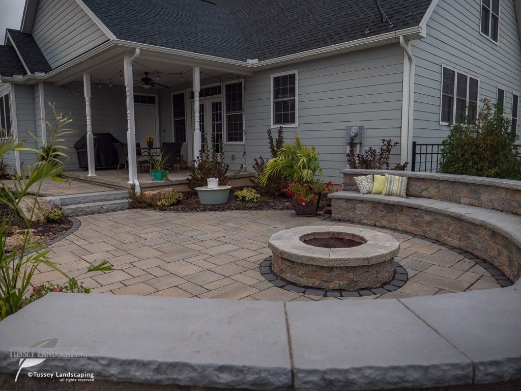 A patio with a fire pit in front of a house.