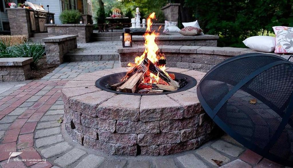A fire pit in the middle of a brick patio.