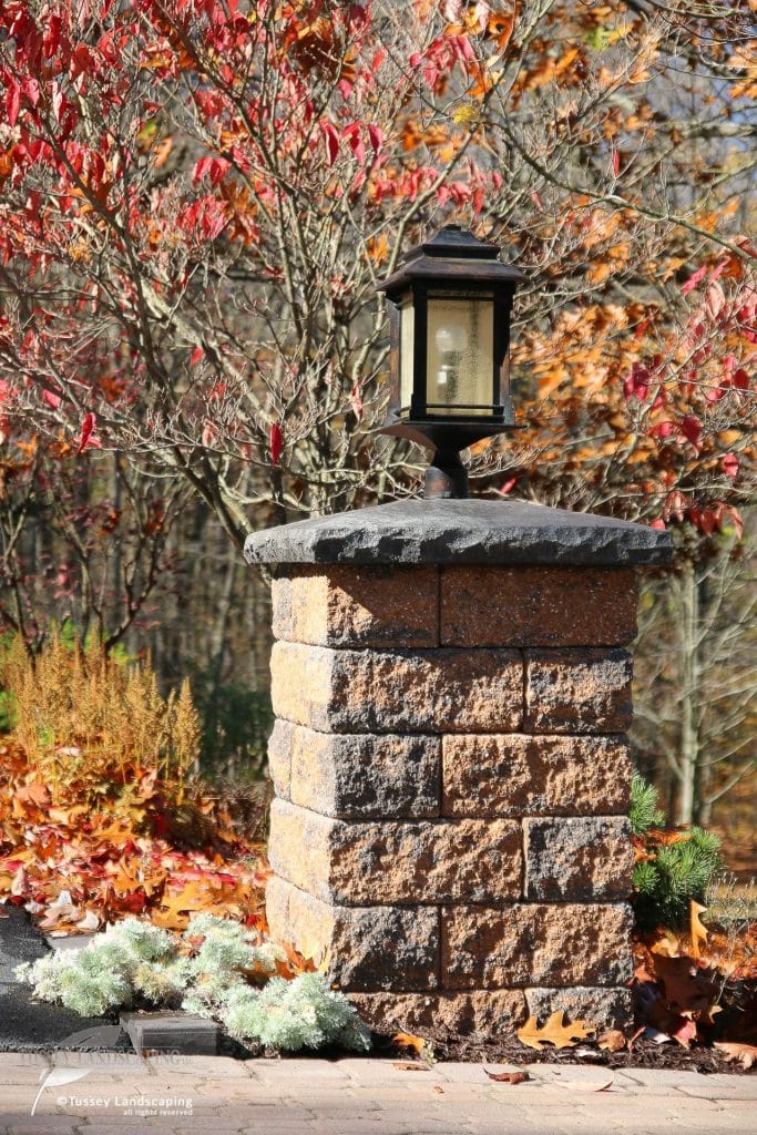 A stone pillar with a lamp on top of it.