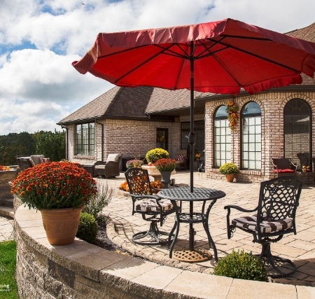A patio with a red umbrella and patio furniture.