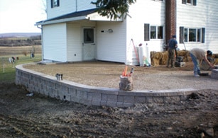 A man is working on a patio in front of a house.
