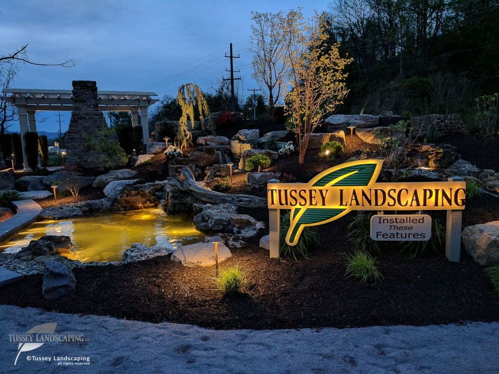 A sign for tussey landscaping at dusk.
