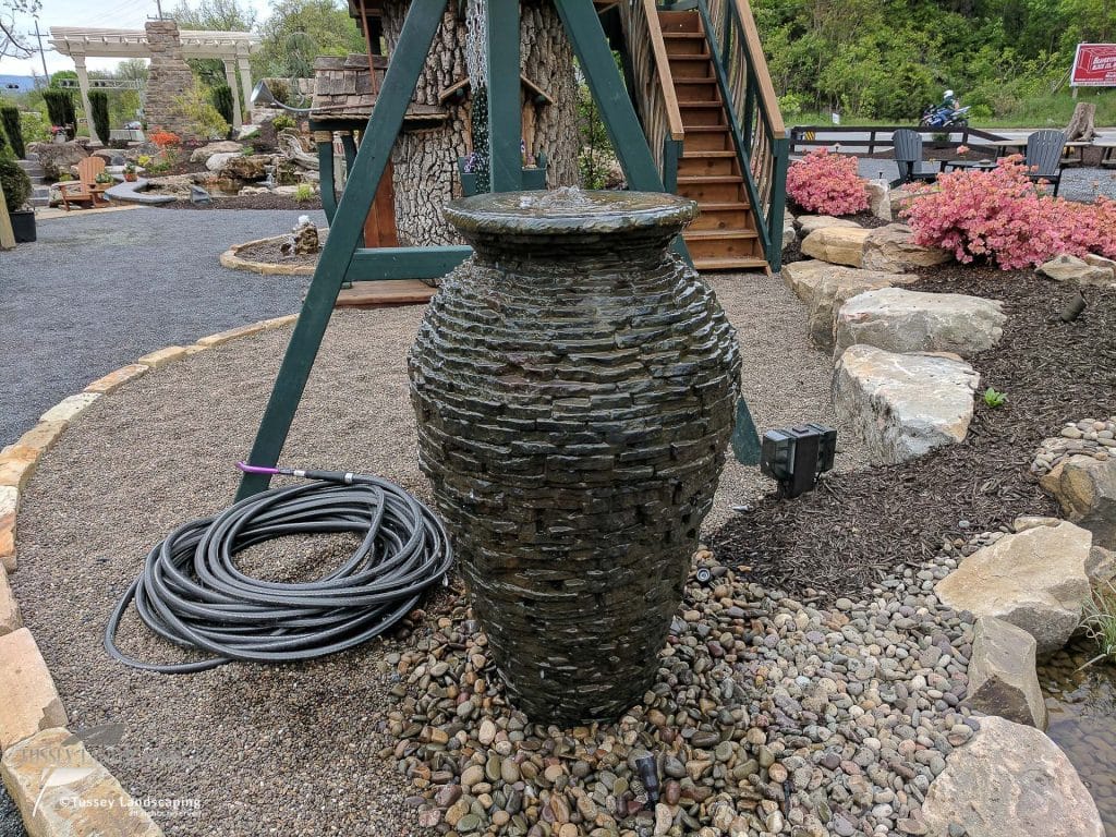 A large stone urn with a hose attached to it.