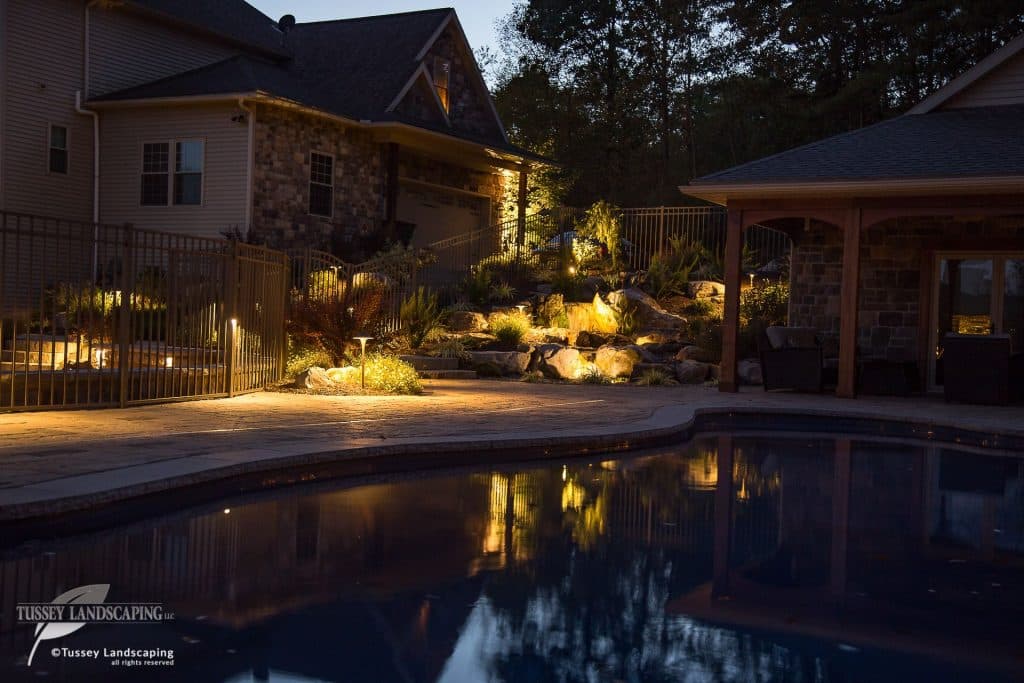 A home with a pool and outdoor lighting at night.