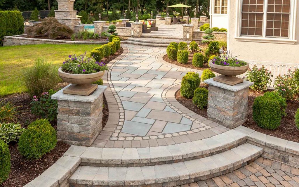 A backyard with a stone walkway and flowerbeds.