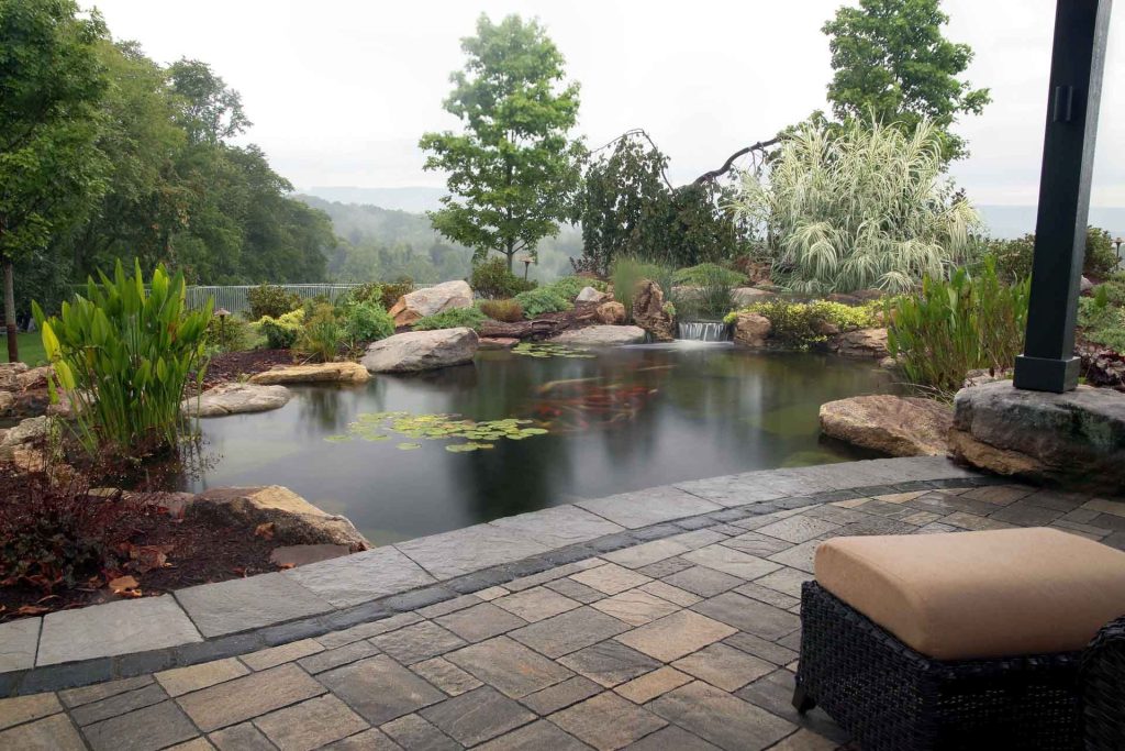 A backyard with a pond and patio furniture.
