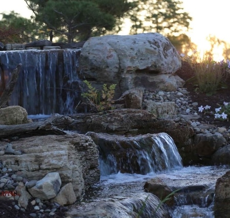 A waterfall with rocks in the middle of a garden.