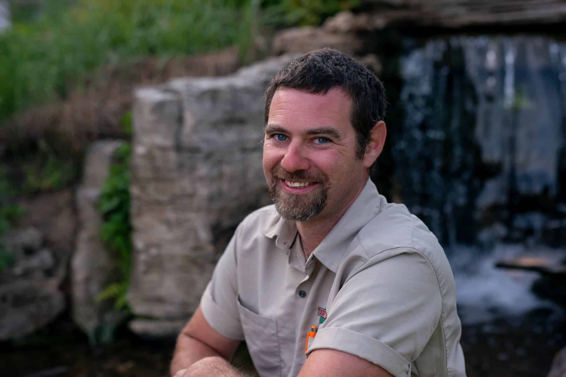 A man sitting in front of a waterfall.