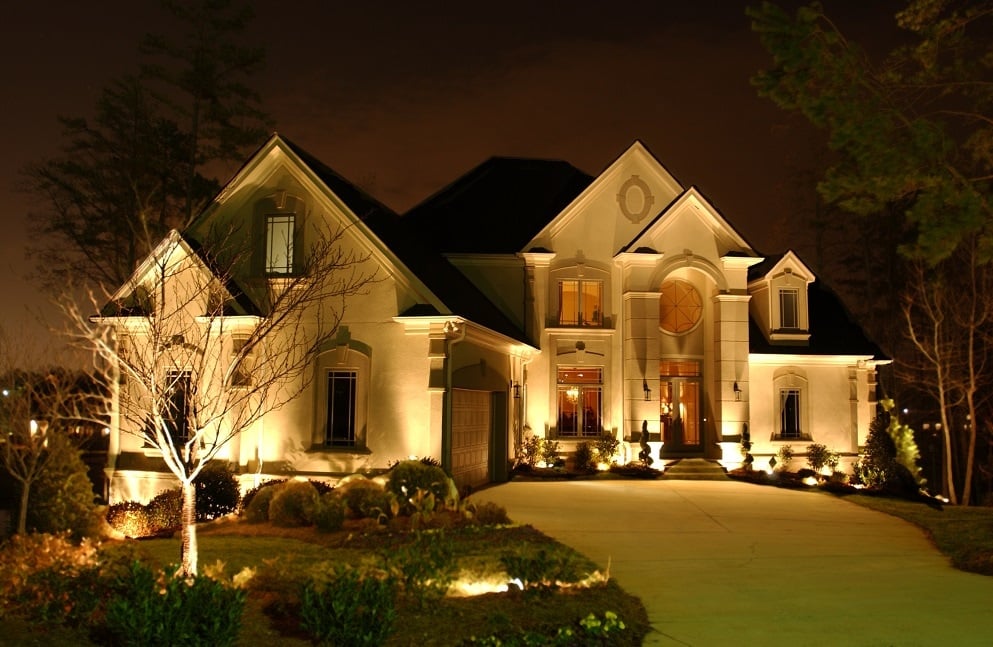 A home is lit up at night with landscape lighting.