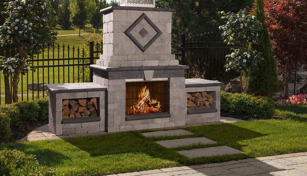 An outdoor fireplace with logs in the middle of a yard.