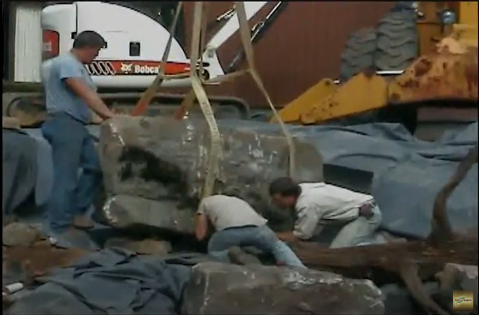 A group of men lifting a large piece of rock.