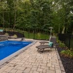 Fiberglass swimming pool with spillway paver patio and pool house and outdoor living space