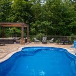 outdoor living space with fiberglass swimming pool, pergola, and paver patio