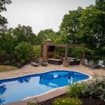 outdoor living space with fiberglass swimming pool, pergola, and paver patio