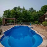 outdoor living space with fiberglass swimming pool, pergola, and paver patio