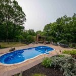 outdoor living space with fiberglass swimming pool, pergola, and paver patio