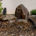 water feature with bubbling boulders in a stone planting bed