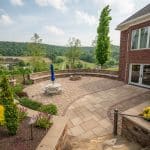 sunken fire pit area with retaining wall and paver patio with landscaping