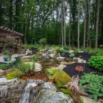 pergola on paver patio with natural stone stairs, landscaping, and mountain boulders