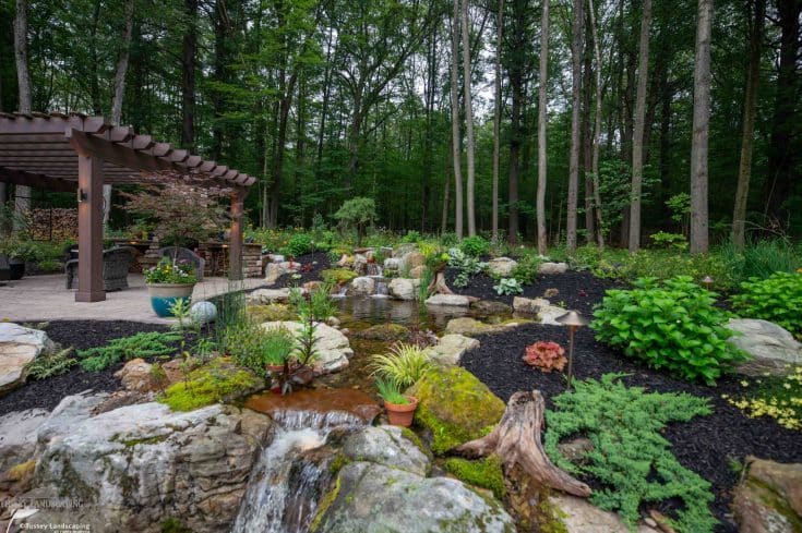 Serene Backyard with Pergola, Water feature, Pond, and Fireplace in Port Matilda, PA