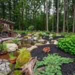 pergola on paver patio with natural stone stairs, landscaping, and mountain boulders