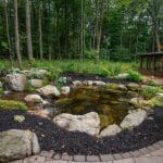 large pond landscaping with mountain boulders and pergola