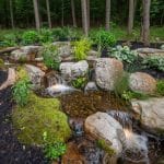 large pond landscaping with mountain boulders and pergola
