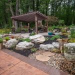 pergola patio with pavers, landscaping, and mountain boulders