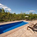 fiberglass swimming pool with hardscaping and paver patio