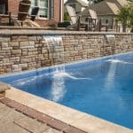 fiberglass swimming pool with hardscaping and paver patio