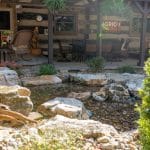 swim pond with retaining wall, paver patio, landscaping, water feature, and waterfalls