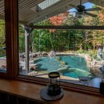 swim pond with retaining wall, paver patio, landscaping, water feature, and waterfalls