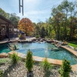 swim pond with retaining wall, paver patio, landscaping, water feature, and waterfalls