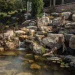 pond with mountain boulders and stream beside a flagstone patio