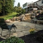 pond with mountain boulders and stream beside a flagstone patio
