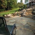 pond with mountain boulders and stream beside a flagstone patio