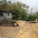 pond with mountain boulders and stream beside a flagstone patio
