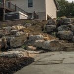 pond with mountain boulders and stream beside a flagstone patio