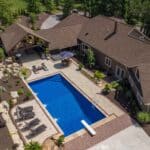 outdoor living space with in ground swimming pool, water falls, water feature, patio, pavers, pavilion, fire pit, natural stone stairs, and retaining walls